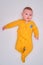 Infant baby lies on a play mat in yellow pajamas, top view. Toddler on the white floor full length, copy space