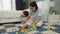 infant baby playing and biting wooden block toy with mother on jigsaw mat in bedroom