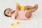 infant baby playing with yellow rubber duck toy on bed