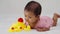 infant baby playing with yellow rubber duck toy on bed