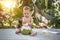 Infant baby at tropical vacation. Picks up and drinks green young coconut with drinking straw