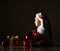 Infant boy toddler in bodysuit and santa claus hat is sitting surrounded by christmas tree balls and gift box, saying