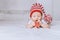 infant child in red and white striped hat with pompom playing with toy angel