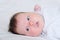 Infant cute baby awaken portrait lying on white sheets