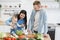 Infant girl mixing salad with metal spoons and mother& x27;s help