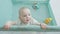 Infant girl standing holding on to edge of playpen