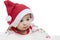 The Infant lies on his stomach in a Santa Claus hat with a surprised, funny face. New Year and Christmas celebration. Close-up.