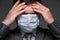 Infected man has a headache and symptoms of the disease, he touches his forehead with his hand, has a protective face mask -