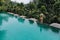 Infinity pool at luxurious exotic island. Back view of woman stay on edge of pool and enjoy jungle view wearing beige