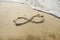 Infinity symbol written on sand.