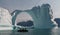 Inflatable boat in front of iceberg arch, Greenland