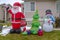 Inflatable Christmas decorations on a grassy yard with snow in winter