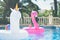 Inflatable colorful white unicorn and pink flamingo at the swim pool. Holidays week in the swimming pool with plastic