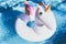 Inflatable colorful white unicorn at the swimming pool. Vacation time in the swim pool with plastic toys. Relaxation and