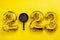 Inflatable golden balloons numbers 2023 with a frying pan on a yellow background. Happy New Year. Cooking. Restaurants