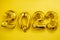 Inflatable golden balloons numbers 2023 on a yellow background. Happy New Year. Flat lay. Copy space. Christmas. Happy