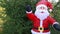Inflatable life-size doll of Santa Claus in a red suit on a background of green trees.