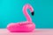 Inflatable mini flamingo on pastel blue and pink background. Pool float party, trendy summer concept. Flat lay, copy space.