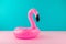 Inflatable pink flamingo on pastel blue and pink background. Pool float party, trendy summer concept.
