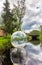 An inflatable transparent ball floats on the surface of a reservoir on the Ruskeala Waterfalls in a forest under a blue sky with