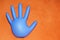 Inflated rubber medical glove on orange background, copy space