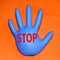 Inflated rubber medical glove with stop sign on orange background
