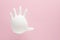 Inflated white medical glove with stop sign gesture on pink background