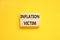 Inflation victim symbol. Concept words Inflation victim on wooden block. Beautiful yellow table yellow background. Business