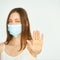 Influenza virus stop gesture. Girl in face mask show deny sign.