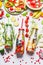 Infused water in bottles with fresh fruits, vegetables and herbs on white background with ingredients