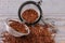 Infuser with dry rooibos leaves on grey wooden table, closeup