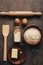 Ingredients for baking on a dark rustic background, flour,milk, butter, eggs, rolling pin, whisk and paddle. Top view, flat lay