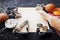 Ingredients for christmas baking. Cookies cutters, flour, rolling pin, eggs and paper sheet on kitchen black table.