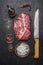 Ingredients for cooking beef steak with salt and pepper carving knife, pepper mill on a dark rustic background top view