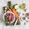 Ingredients for cooking dinner - raw beef meat, carrots, squashes, onions, garlic, thyme, spices, olive oil.