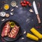 Ingredients for cooking double raw lamb ribs in a cast iron frying pan with vegetables and spices on dark blue wooden rustic back