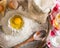 Ingredients for cooking dough or bread. Broken egg on top of a bunch of white rye flour. Dark wooden background.