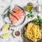 Ingredients for cooking lunch - raw salmon, dry pasta tagliatelle, cream, olive oil, spices and herbs. On a light background