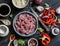 Ingredients for cooking meat stir fry with vegetables and rice - raw meat, sweet red pepper, red onion, rice, spices, on dark wood