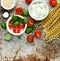 Ingredients for cooking pasta caprese - fresh basil, cherry tomatoes, baby mozzarella cheese, fresh pasta fusilli lunghi and