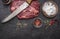 Ingredients for cooking raw beef steak with salt and pepper carving knife pepper mill dark rustic background top view horizon