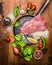 Ingredients for cooking turkey steak with rice seasoning vegetables in a frying pan on a wooden rustic background top view