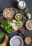 Ingredients for a healthy breakfast - chia pudding, oatmeal, banana, kiwi, spinach, coconut milk on a dark background, top view.