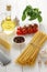 Ingredients for healthy mediterranean diet: pasta bucatini or with fresh vegetables, cheese, oil on white wooden table.