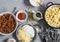 Ingredients for making mac and cheese. Pasta, cheese, meat tomato sauce on a gray background, top view.