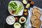 Ingredients for making toast sandwiches with avocado, asparagus, tomatoes and soft cheese on dark background, top view.