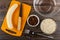 Ingredients for oat cookies. Peeled banana, knife on cutting board, empty bowl, bowls with raisin, oat flakes, fork on table. Top