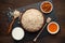 Ingredients for oatmeal on rustic wooden background: rolled oat flakes, milk, honey and raisins.