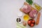 Ingredients for ossobuco, beef shank stew on a bone with carrots, tomatoes and celery on a light concrete background. Main meat