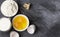 Ingredients for pastries: flour, eggs, milk against a dark background